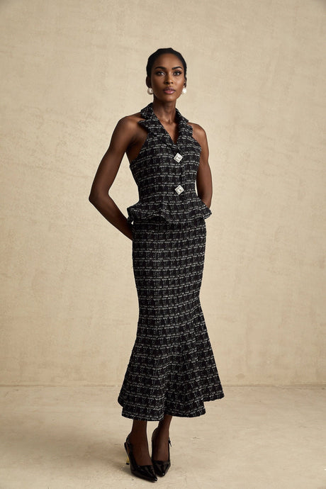 Young woman wearing a black and white checked tweed matching set consisting of a sleeveless vest top and skirt