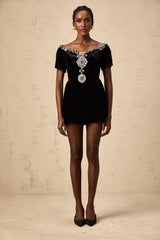 Young woman wearing a black velvet mini dress with embellishments named Camille standing in a stylish pose
