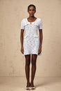 Young woman wearing a blue checked knit mini dress with short sleeves and a fitted silhouette standing against a plain background