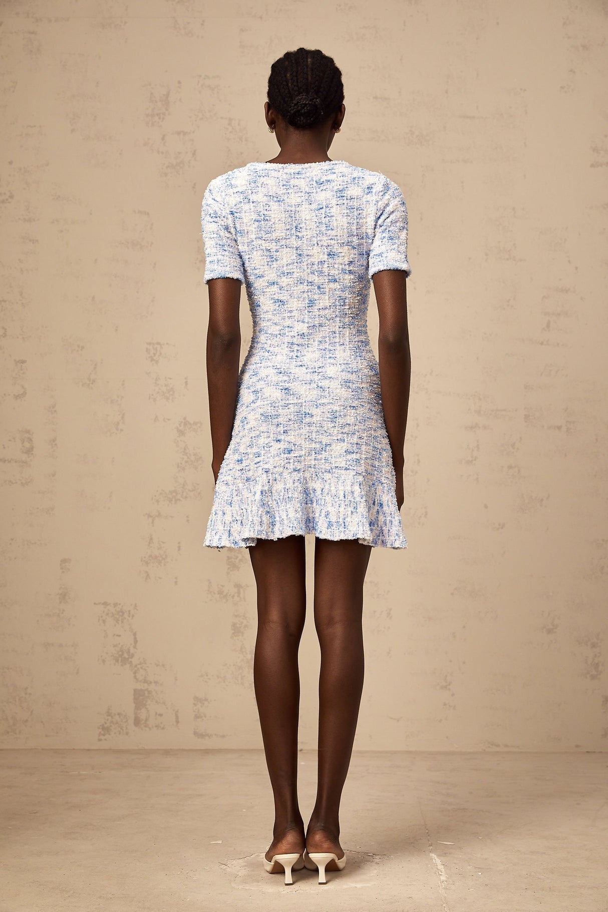 Young woman wearing a blue checked knit mini dress with short sleeves and a fitted silhouette