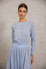 Young woman wearing a blue knitted top and matching skirt set adorned with rhinestone embellishments