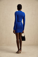 Young woman wearing a blue knitted two piece outfit consisting of a top with button details and a matching skirt