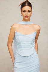 Young woman wearing a blue matching set with ruched tulle top and skirt standing against a plain background