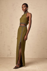 Young woman wearing a bright green matching set consisting of a sleeveless top and skirt with daisyinspired beaded trim along the edges