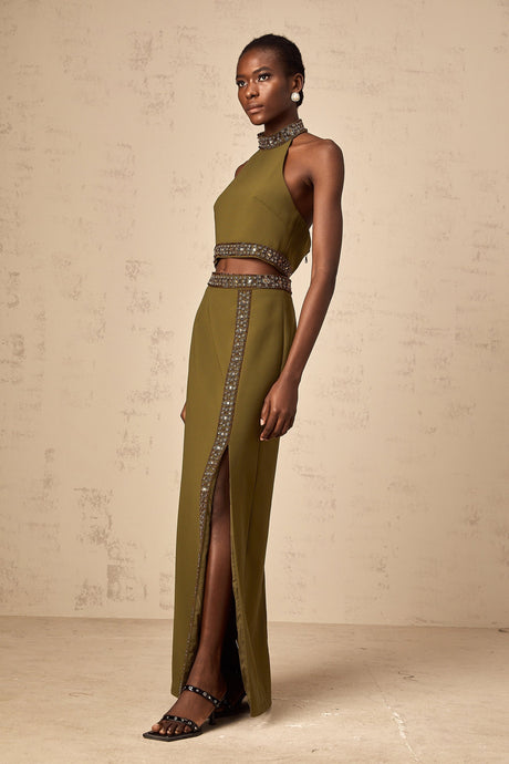 Young woman wearing a bright green matching set consisting of a sleeveless top and skirt with daisyinspired beaded trim along the edges