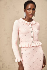 Young woman wearing a pink argyle patterned knitted cardigan paired with a matching skirt in a coordinated set