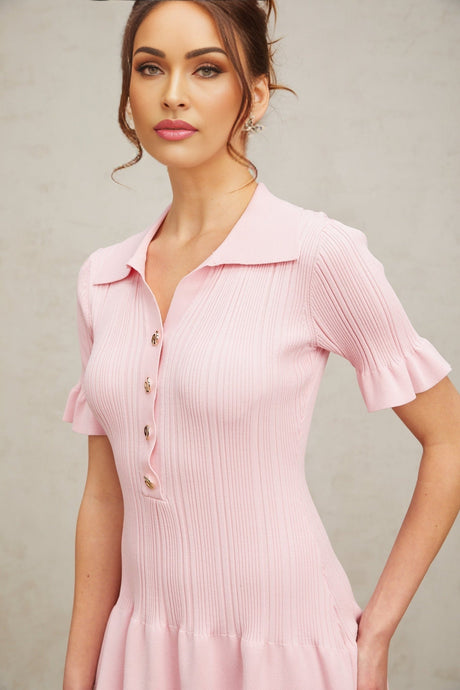 Young woman wearing a pink mini dress with flared short sleeves and skirt made of fine knit fabric