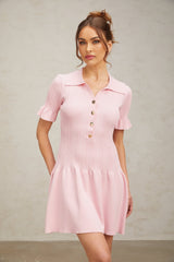 Young woman wearing a pink mini dress with flared skirt and long sleeves made of fine knit fabric