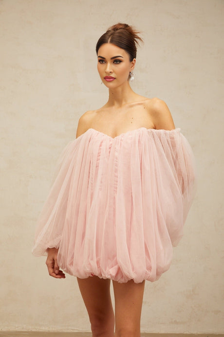 Young woman wearing a pink mini dress with layered bubble tulle skirt standing in a casual pose