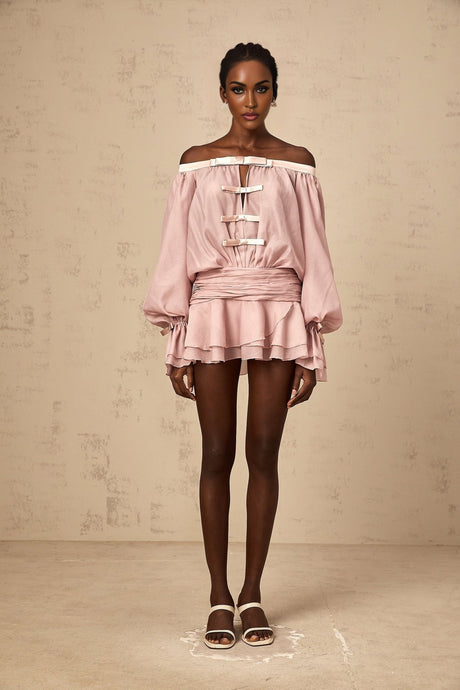 Young woman wearing a pink offshoulder mini dress with bow detail and ruffled hem