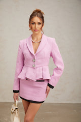 Young woman wearing a pink tweed matching set consisting of a sleeveless top and short skirt with frayed edges and gold button details
