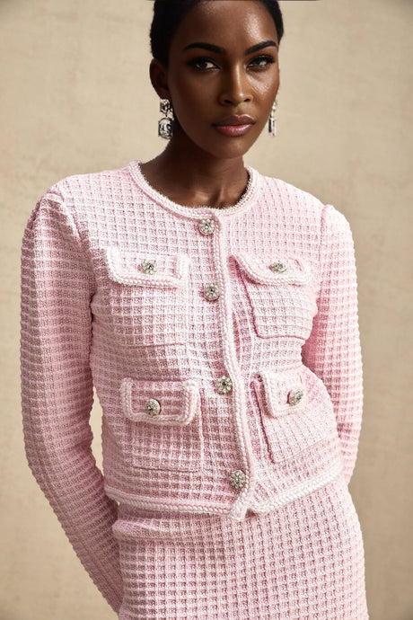 Young woman wearing a pink waffle knit jacket and matching skirt set standing in a casual pose