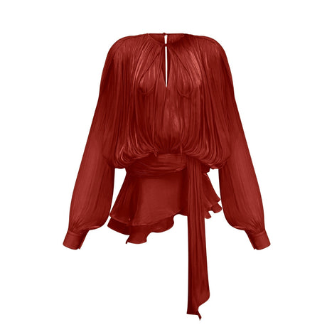 Young woman wearing a red mini dress with full pleats and ruffles standing in a neutral setting