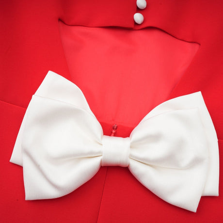 Young woman wearing a red mini dress with petal sleeves and cutout detail featuring a bow accent