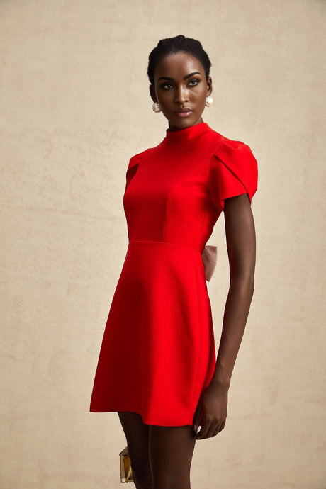 Young woman wearing a red mini dress with petal sleeves cut out details and bow accent