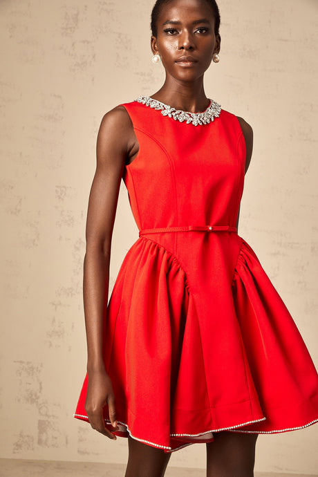 Young woman wearing a red mini dress with pleated skirt and embellished bodice