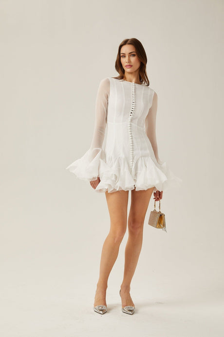 Young woman wearing a semi sheer flared mini dress with a floral pattern standing in a neutral background