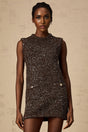 Young woman wearing a short barleybrown knit dress covered in shimmering sequins with a formfitting silhouette