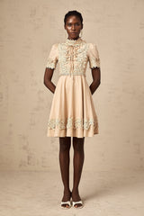 Young woman wearing a short flared dress with corded lace detailing and long sleeves