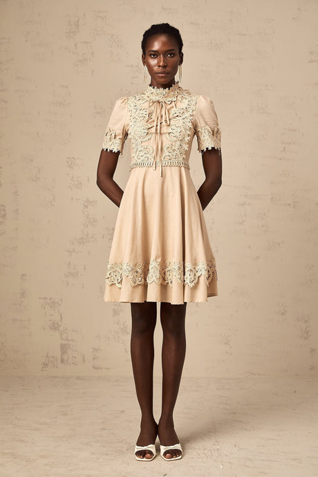 Young woman wearing a short flared dress with corded lace detailing and long sleeves
