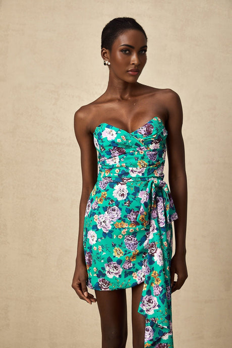 Young woman wearing a short green dress with floral pattern and ruched detailing