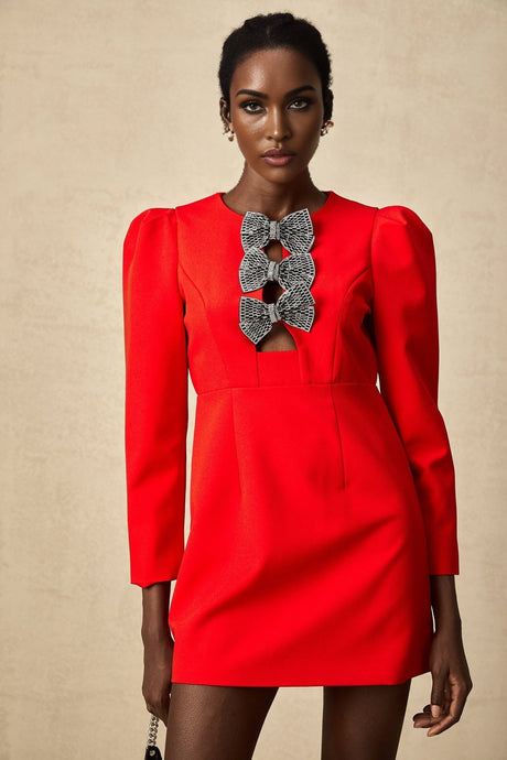 Young woman wearing a short red dress with a split skirt and studded bow detail