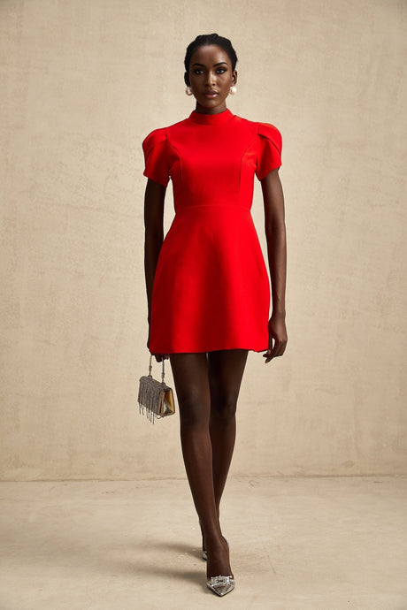 Young woman wearing a short red dress with petal sleeves and a cutout design featuring a bow detail