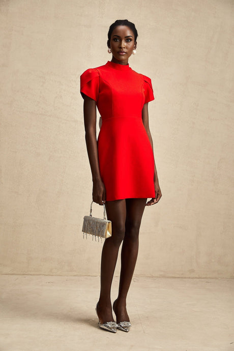 Young woman wearing a short red dress with petal sleeves and a cutout detail featuring a bow accent
