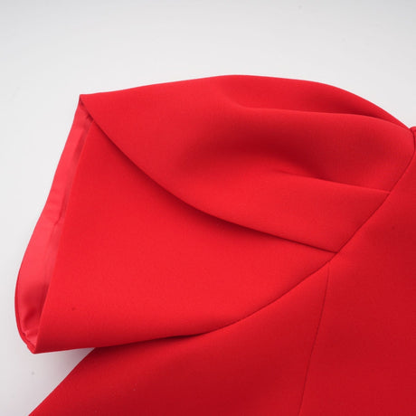 Young woman wearing a short red dress with petal sleeves and a cutout detail featuring a bow