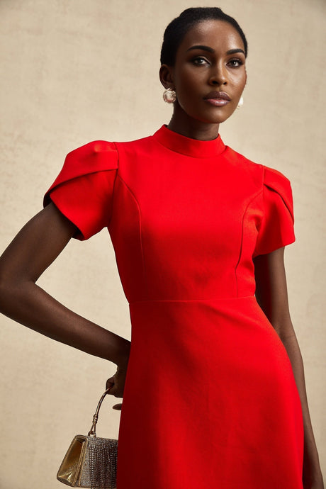 Young woman wearing a short red dress with petal sleeves and a cutout detail featuring a bow