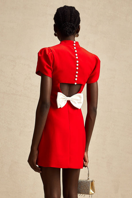 Young woman wearing a short red dress with petal sleeves and a cutout detail with bow accent