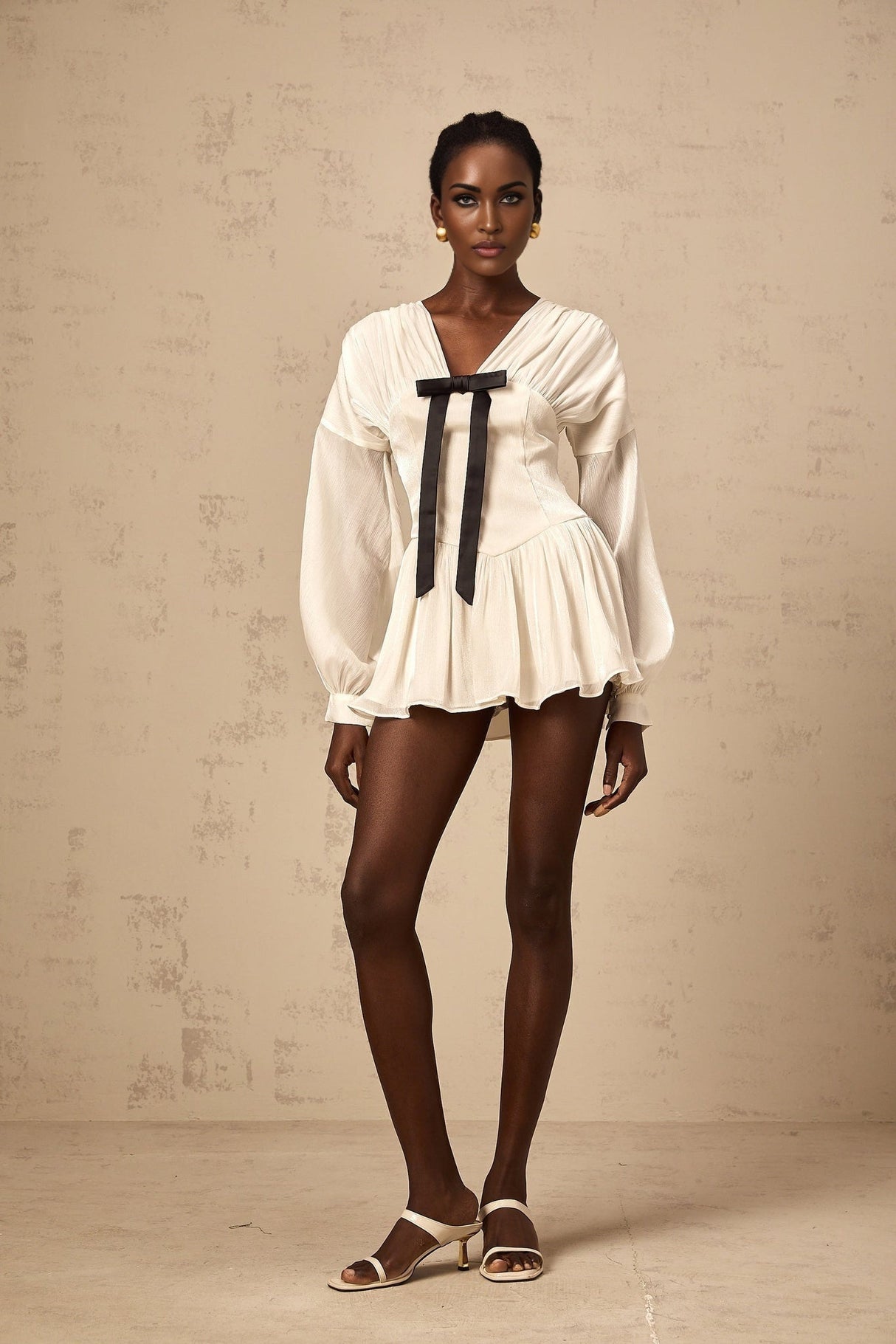 Young woman wearing a short white dress with a bow detail and glitter accents