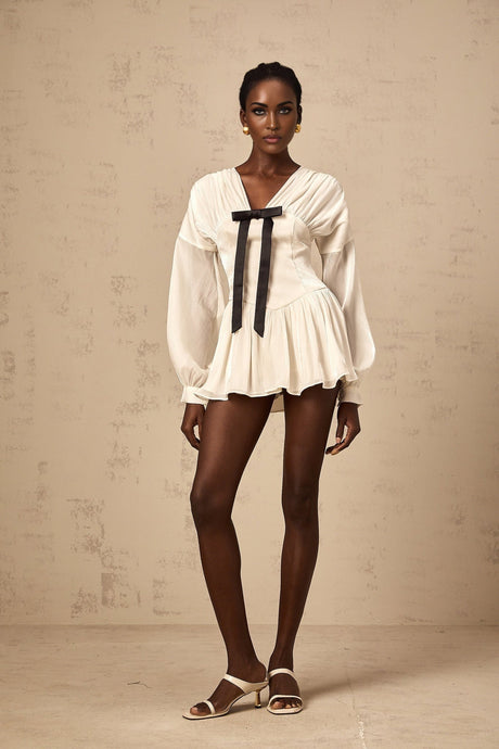 Young woman wearing a short white dress with a bow detail and glitter accents