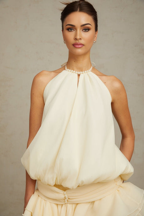 Young woman wearing a short white halterneck dress with faux pearl embellishments