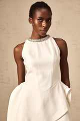 Young woman wearing a short white mini dress with crystal embellishments and layered design standing in a stylish pose