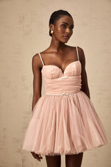 Young woman wearing a sleeveless white tulle mini dress with pleated details and a flared skirt