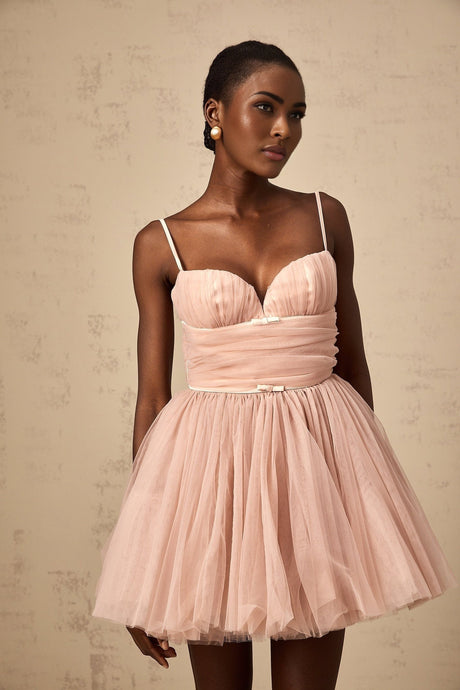 Young woman wearing a sleeveless white tulle mini dress with pleated details and a flared skirt