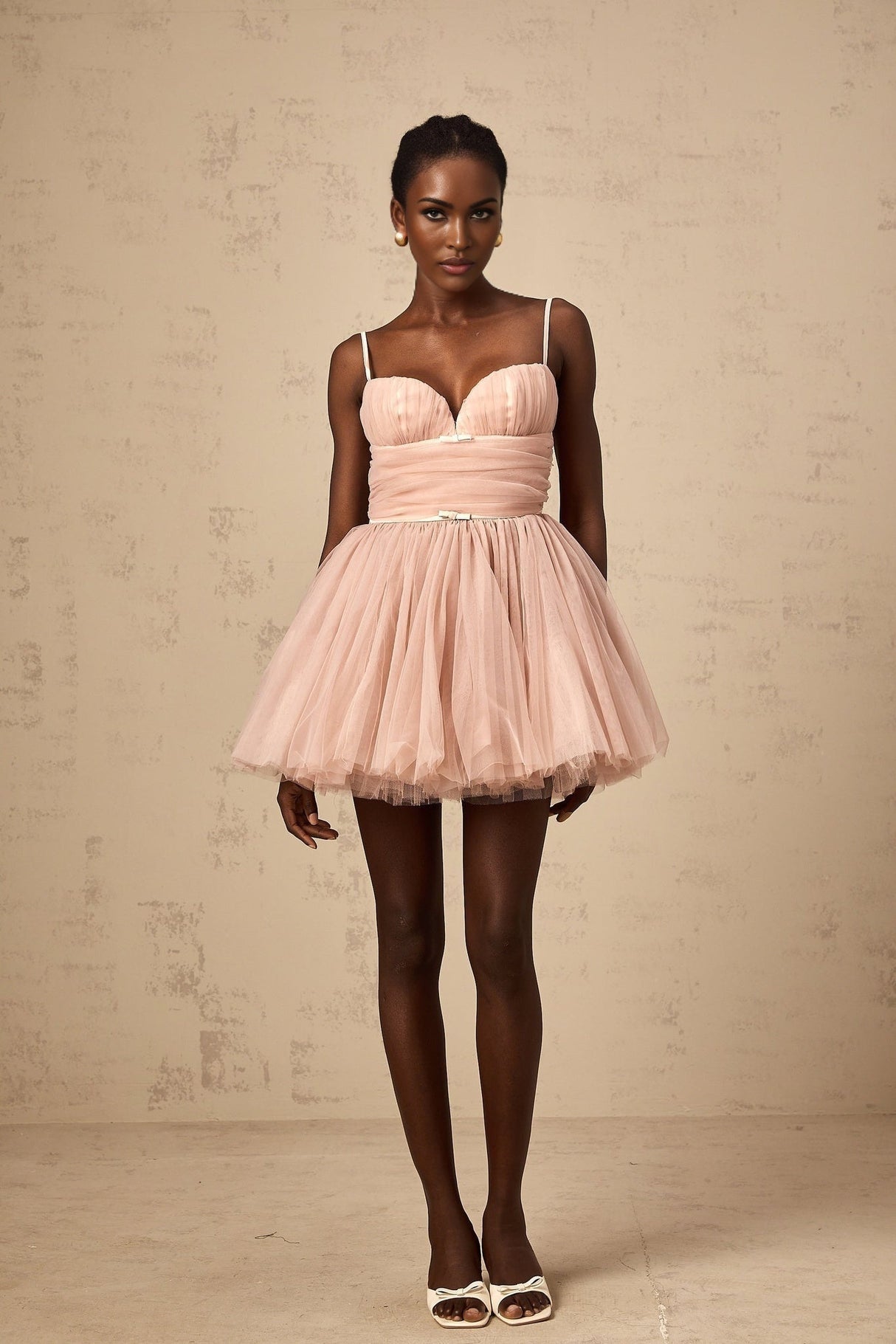 Young woman wearing a sleeveless white tulle mini dress with pleated details and a flowy skirt