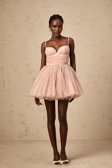 Young woman wearing a sleeveless white tulle mini dress with pleated details and a flowy skirt