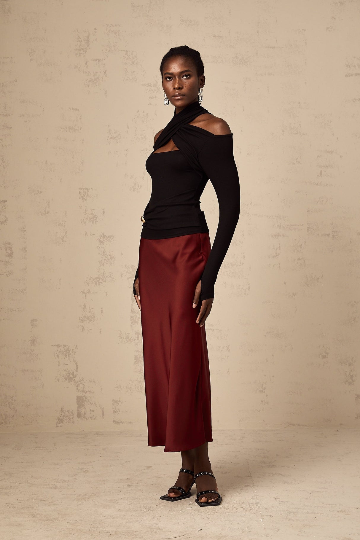 Young woman wearing a vibrant red satin skirt with a flared silhouette standing against a plain background