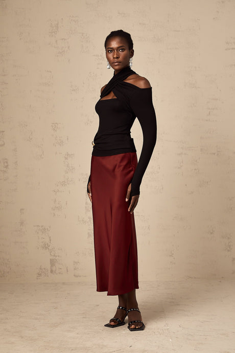 Young woman wearing a vibrant red satin skirt with a flared silhouette standing against a plain background