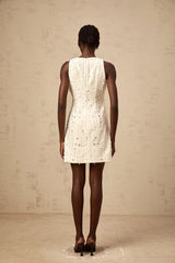 Young woman wearing a white Aline mini dress with embellishments standing in a neutral background