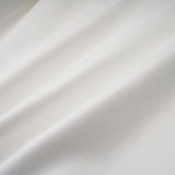 Young woman wearing a white halterneck mini dress with ruffled details standing in a casual pose
