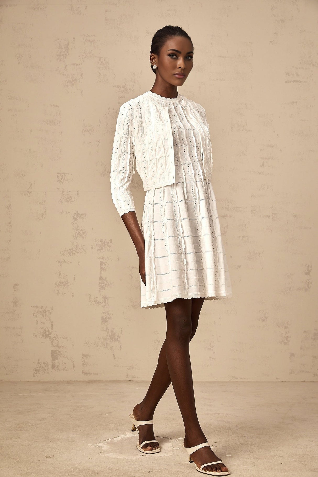 Young woman wearing a white knitted cardigan with ruffled details