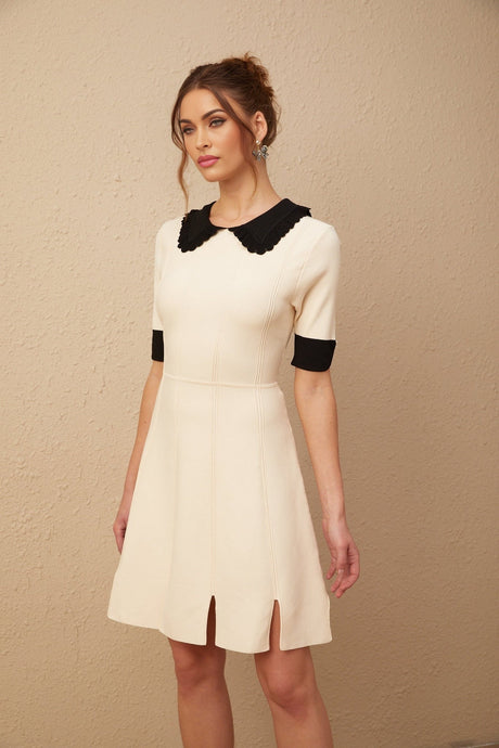 Young woman wearing a white knitted mini dress with split hem detail standing in a casual pose
