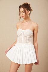 Young woman wearing a white lace top and matching skirt set standing in a casual pose