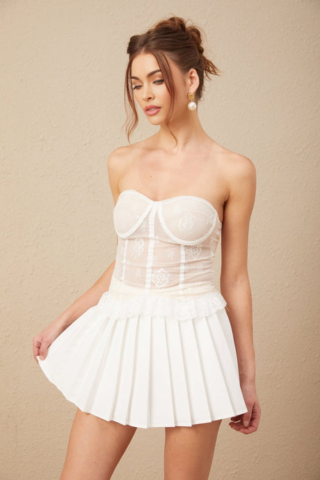 Young woman wearing a white lace top and matching skirt set standing in a casual pose