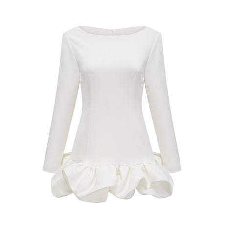 Young woman wearing a white mini dress with a bubble skirt and short sleeves standing against a plain background