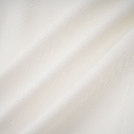 Young woman wearing a white mini dress with a bubble skirt and short sleeves standing against a plain background