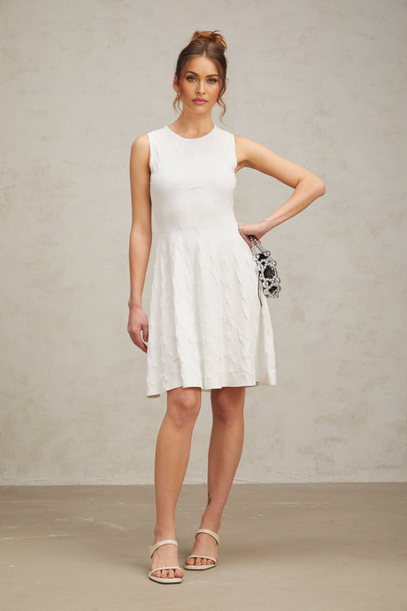 Young woman wearing a white mini dress with a jasmine star pattern knitted design